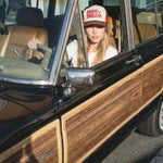 Dare to Dream brown vintage trucker hat worn by woman sitting in classic car, lifestyle shot