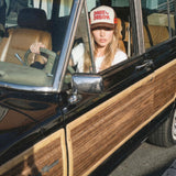 Dare to Dream brown vintage trucker hat worn by woman sitting in classic car, lifestyle shot