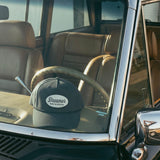 Dreamer Refuse the Status Quo navy trucker hat resting on vintage car dashboard, lifestyle product shot