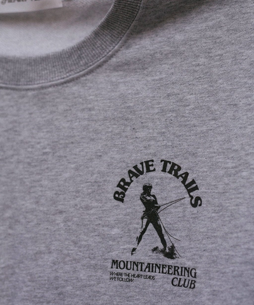 Gray sweatshirt with 'Brave Trails Mountaineering Club' logo on a close-up view