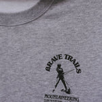 Gray sweatshirt with 'Brave Trails Mountaineering Club' logo on a close-up view