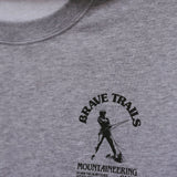 Gray sweatshirt with 'Brave Trails Mountaineering Club' logo on a close-up view