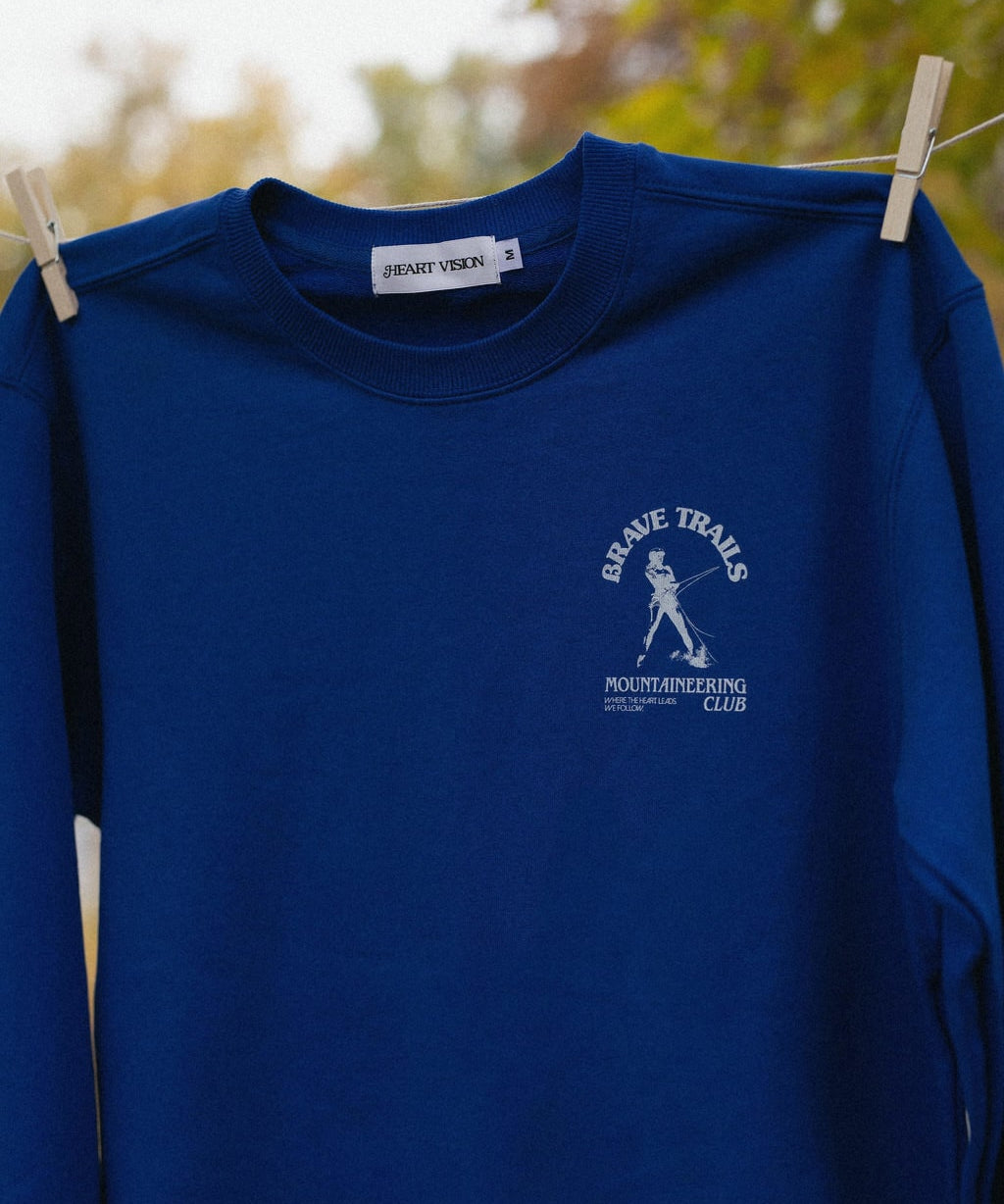 Blue sweatshirt with close up of a logo on a clothesline against a blurred natural background