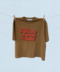 Brown t-shirt with red text 'Fortune Favors the Bold' hanging on a clothesline against a light blue background.