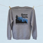 Back of gray sweatshirt with 'Brave Trails Mountaineering Club' design hanging on a clothesline on a light blue background