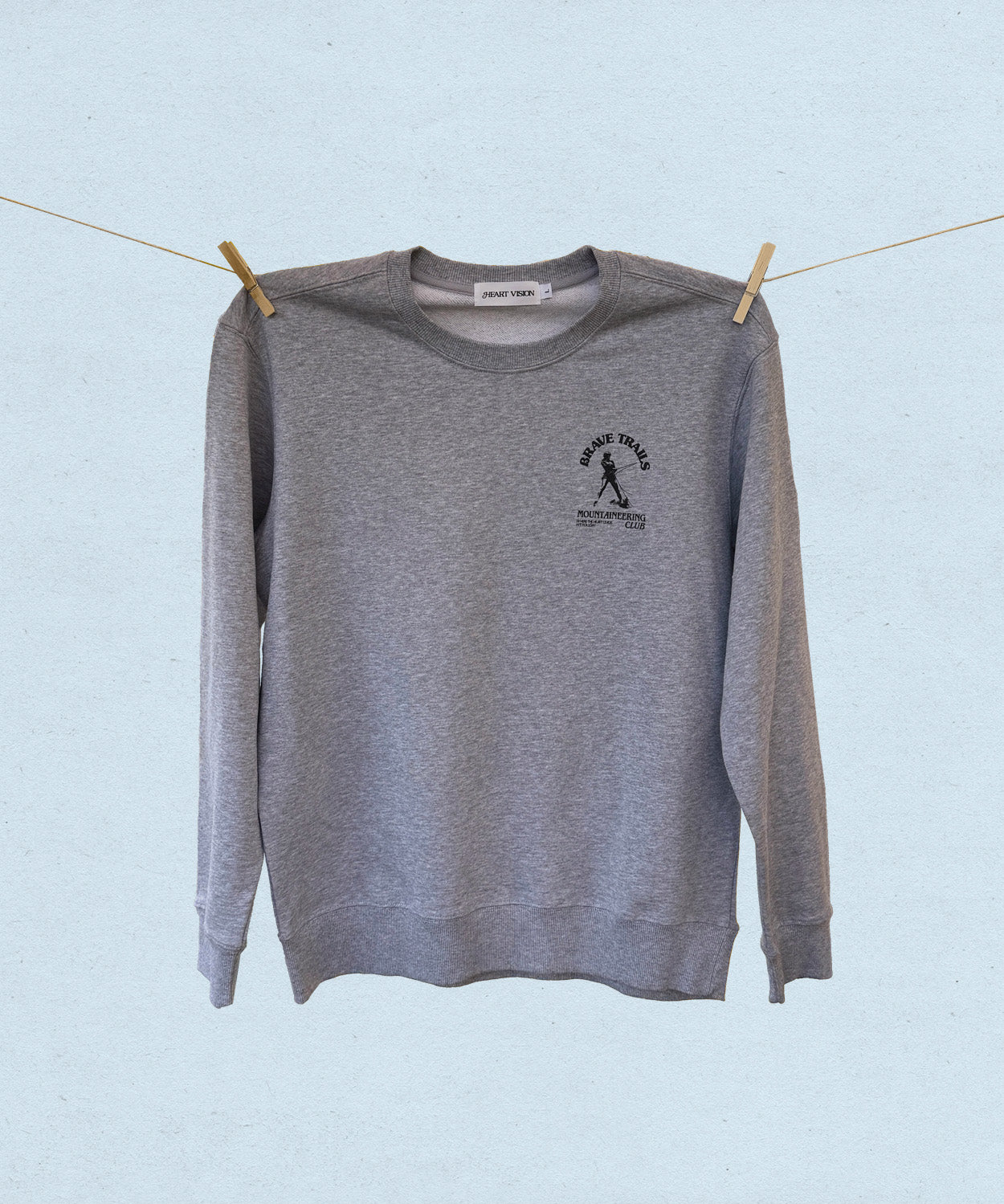Gray sweatshirt with a logo on a clothesline against a light blue background