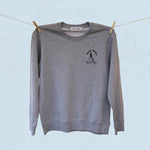 Gray sweatshirt with a logo on a clothesline against a light blue background