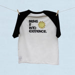 Back of white baseball t-shirt with black short sleeves and text 'Bring it into existence' on a light blue background