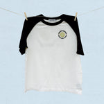 Black and white baseball t-shirt with a logo on a light blue background
