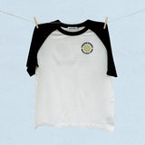 Black and white baseball t-shirt with a logo on a light blue background