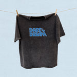Black t-shirt with 'Dare to Dream' text on a clothesline against a light blue background