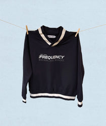 Navy sweater with white trim and  'Set the Frequency, become the magnet' text on a light blue background
