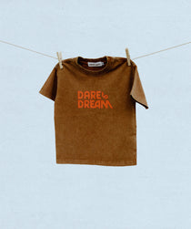 Brown t-shirt with red/orange 'Dare Dream' text on a clothesline against a light blue background