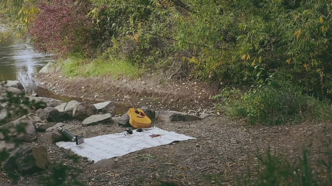 family walking up to picnic blanket by the river. They are wearing intentional apparel by Heart Vision with phrases "dare to dream" and "the universe has my back"