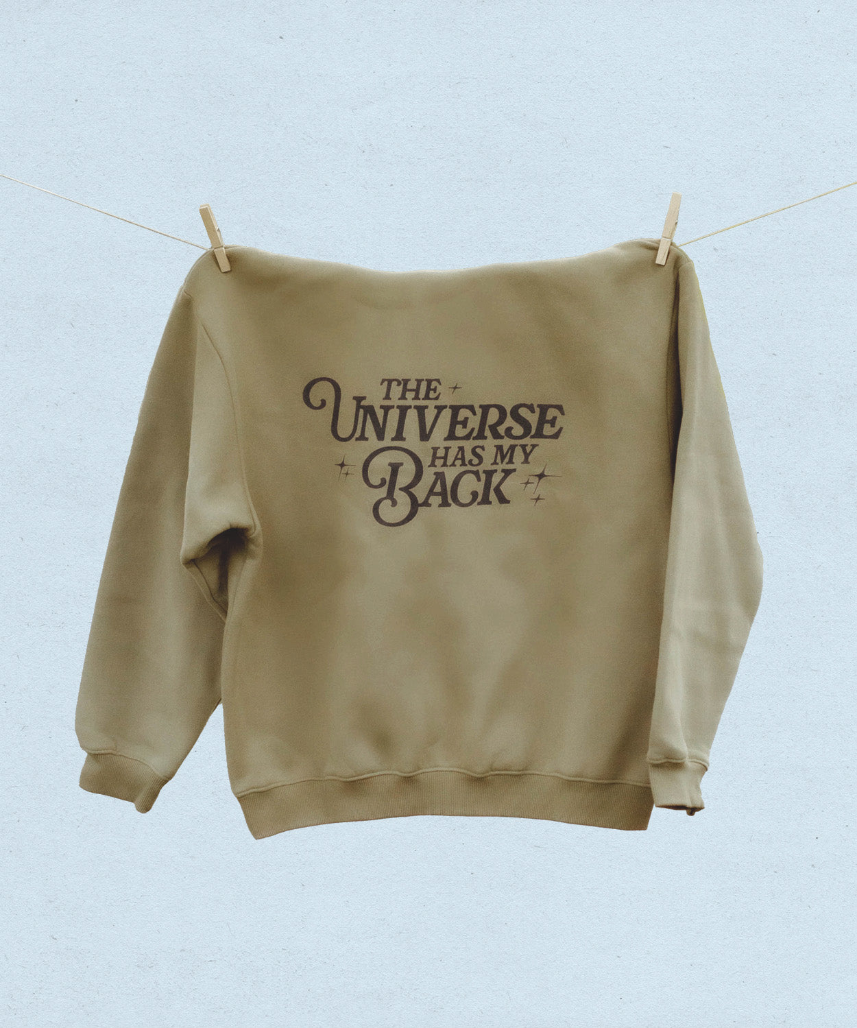 Back of khaki hooded sweatshirt with 'The Universe Has My Back' text on a light blue background